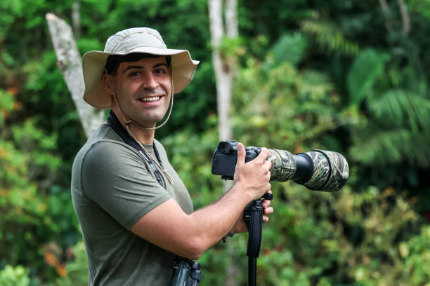 Wildlife photographer holding camera with telephoto lens in forest capturing nature and animals
