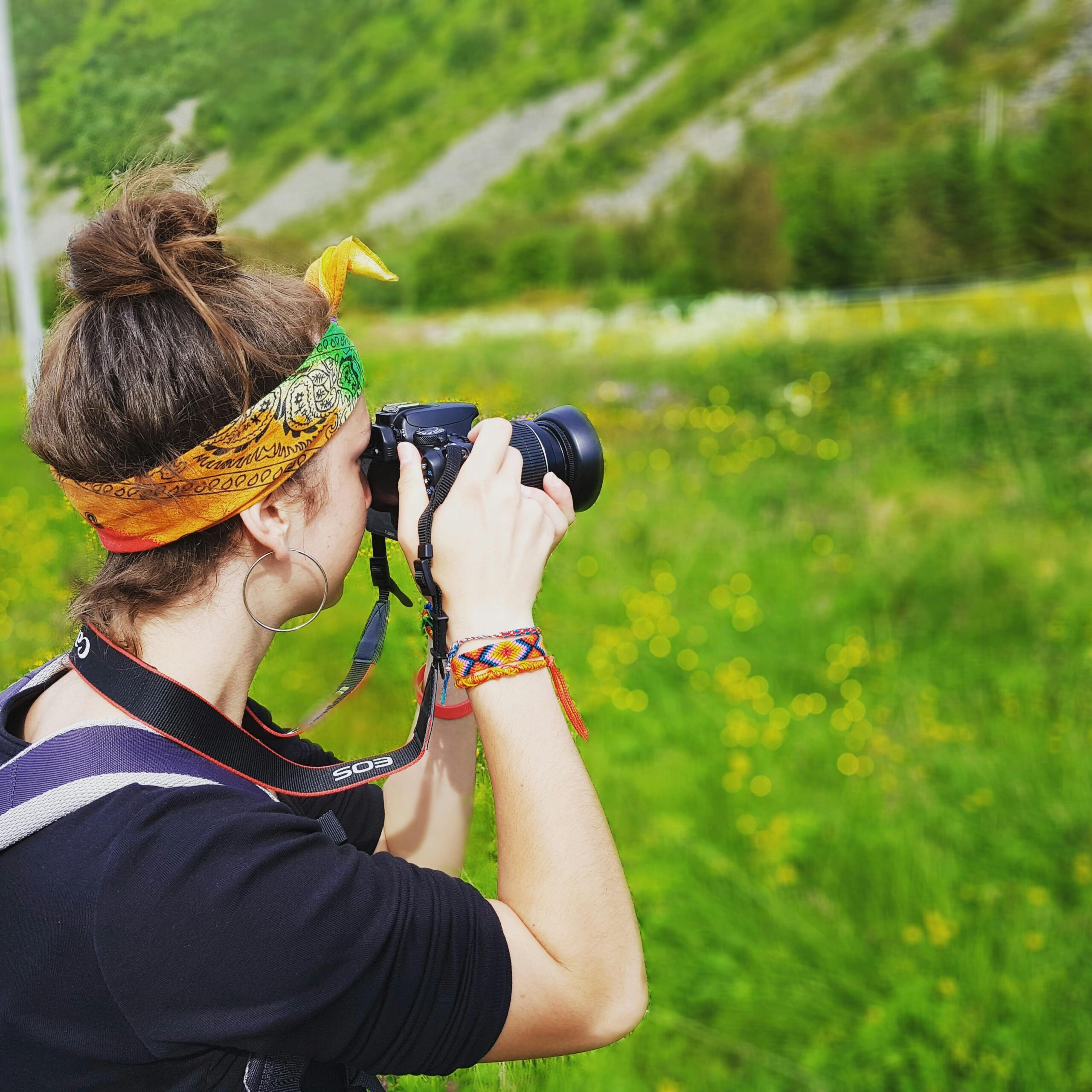 A woman photographing a lush green landscape in Vågan, Norway during daytime.