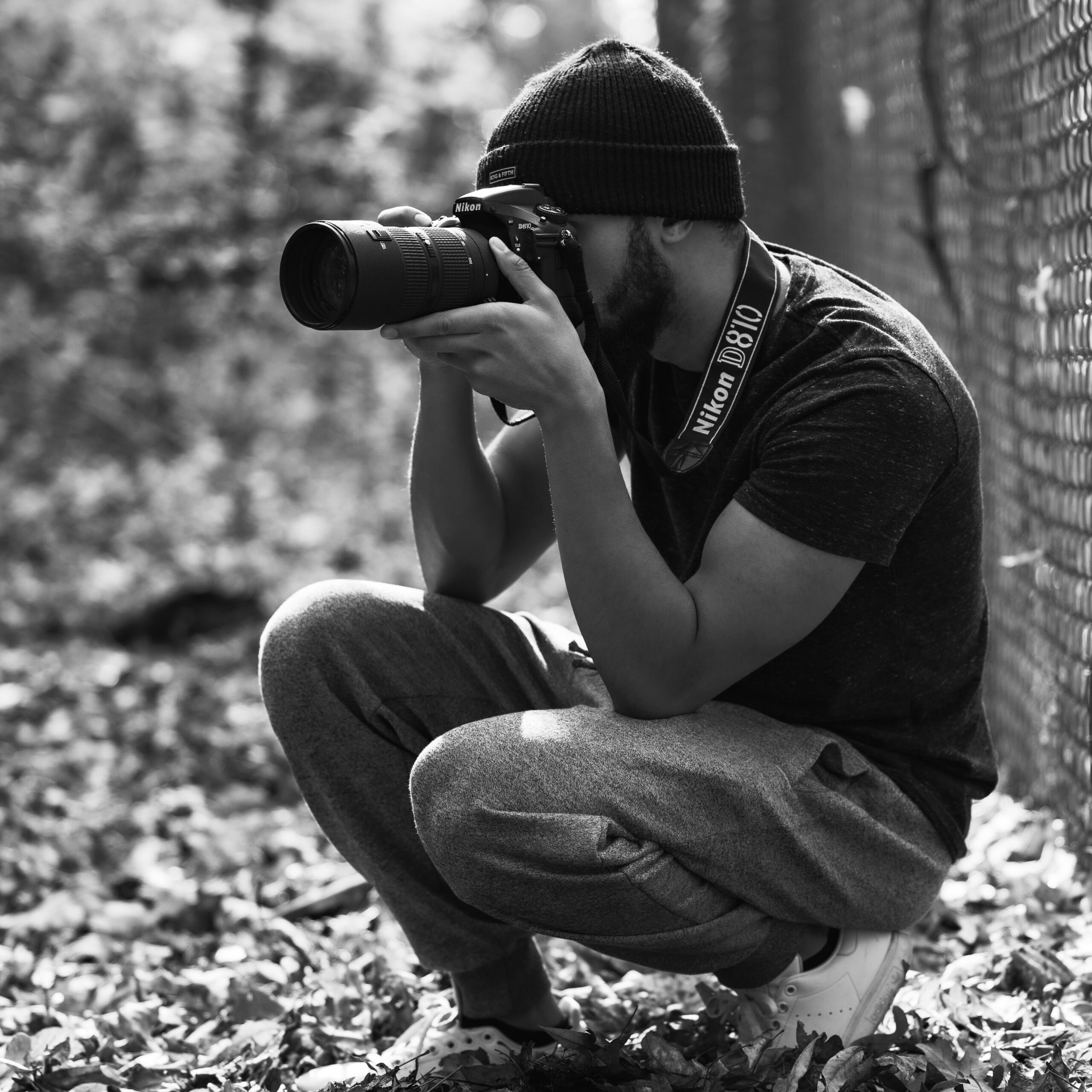 A photographer crouching in nature capturing moments with a DSLR camera.