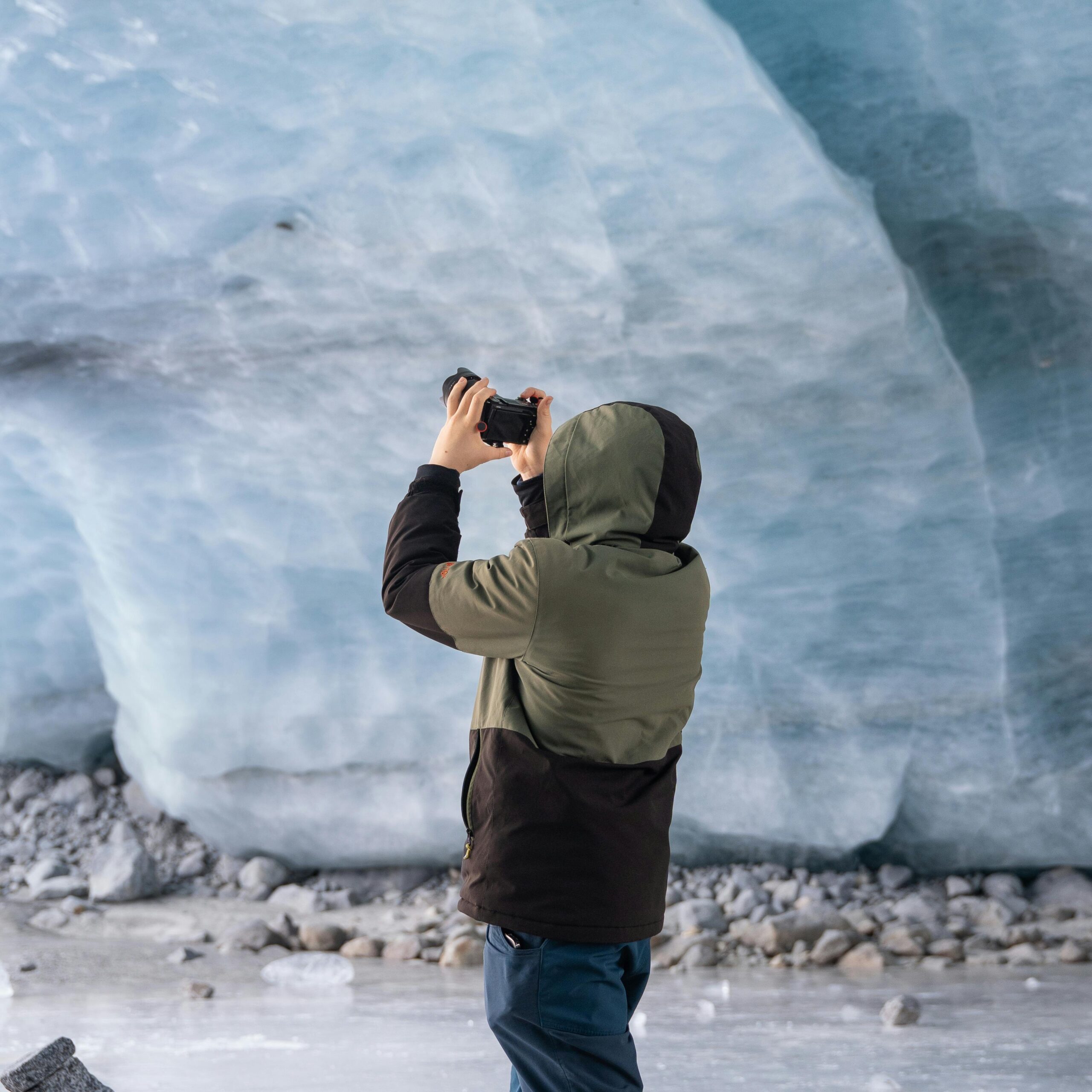 Person photographing inside an ice cave, highlighting winter exploration.